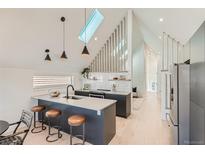 Bright kitchen boasts skylight, sleek cabinetry, island with seating, and stainless steel refrigerator at 1101 S Dahlia St, Denver, CO 80246
