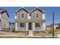 Charming two-story home featuring a welcoming front porch with classic columns and a well-maintained lawn at 18049 E 106Th Ave, Commerce City, CO 80022