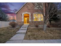 Charming stucco home featuring a brick facade, arched entryway, and landscaped front yard at 12997 Wyandot Way, Westminster, CO 80234