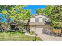 Charming home with a stone facade, well-manicured lawn, mature trees, and an attached two-car garage at 5543 S Kenton Ct, Englewood, CO 80111