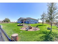 Spacious backyard featuring a fire pit, swing, and lush green grass with picturesque rural views at 11499 County Road 40 1/2 Rd, Platteville, CO 80651