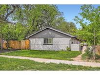 Charming single-story home featuring a well-maintained lawn, gray painted brick and mature shade trees at 2955 N Gilpin St, Denver, CO 80205