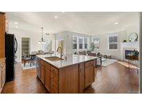 Open kitchen featuring a large island with granite countertops and hardwood floors flowing into the living area at 10822 E 28Th Pl, Denver, CO 80238