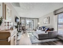 Bright living room with a gray sectional sofa, wood floors, and sliding glass doors to a balcony at 2740 W 86Th Ave # 190, Westminster, CO 80031