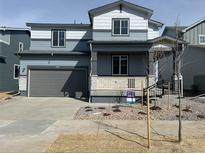 Two-story home featuring a covered porch, gray siding, and an attached two-car garage at 1401 Bloom St, Brighton, CO 80601