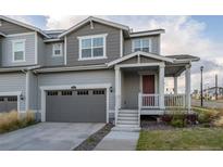 Charming townhome featuring a covered front porch, attached garage, and neutral gray siding at 9590 Sedalia St, Commerce City, CO 80022