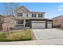 Charming two-story home featuring a three-car garage, covered porch, and manicured front lawn at 4830 S Versailles St, Aurora, CO 80015