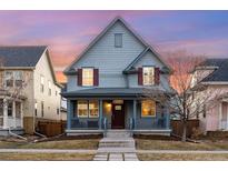 Charming two-story home featuring a welcoming front porch and red shutters against a blue exterior at dusk at 3269 Uinta St, Denver, CO 80238