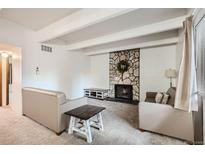 Cozy living room with stone fireplace, neutral furniture, and bright overhead lighting at 384 S Ironton St # 208, Aurora, CO 80012