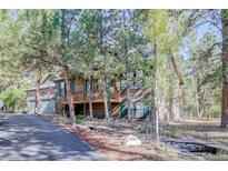 Charming two-story cabin-style home nestled among the trees with a spacious deck and inviting curb appeal at 1065 Independence Dr, Larkspur, CO 80118