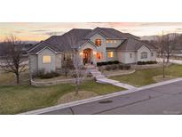 Stunning stucco home boasts a beautifully landscaped front yard and inviting arched entryway at 16394 W 77Th Ln, Arvada, CO 80007