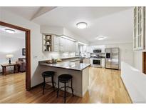 Bright kitchen features white cabinets, granite countertops, stainless steel appliances, and breakfast bar at 3298 S Krameria St, Denver, CO 80222