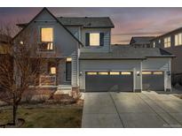 Charming home boasts a three-car garage and classic architectural details, set against a vibrant twilight sky at 11404 Lovage Way, Parker, CO 80134