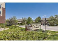 Eye-level sign reading '5401 Village Plaza Lofts' with mature landscaping and residential buildings in the background on a sunny day at 5401 S Park Terrace Ave # 109A, Greenwood Village, CO 80111