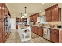 Spacious kitchen with stainless steel appliances, custom cabinets and a marble island counter top at 7631 Oak St, Arvada, CO 80005