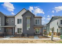 Modern two-story townhome with gray siding and a well-manicured front yard and black metal fence at 6912 Huddersfield Ln, Castle Pines, CO 80108