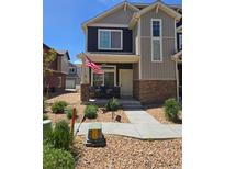 Charming two-story home with stone accents and a welcoming front porch with American flag at 18006 E 103 Ave, Commerce City, CO 80022