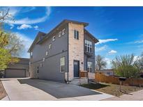 Modern two-story home featuring gray siding, stone accents, and a well-manicured front yard with a long driveway at 5470 Krameria St, Commerce City, CO 80022