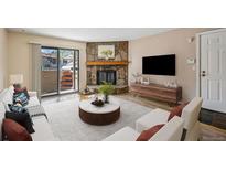 Inviting living room with a stone fireplace and sliding glass door to a private patio at 7720 W 87Th Dr # J, Arvada, CO 80005