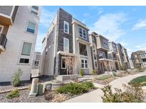 Modern townhome with gray siding, stone accents, and landscaped front yard at 11918 Mountview Ln, Broomfield, CO 80021