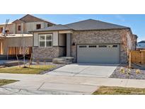 Beautiful single-Gathering home with stone accents, a gray roof, attached two-car garage, and newly installed front yard at 6050 Hourglass Dr, Brighton, CO 80601
