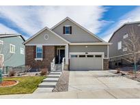 Inviting home with two-car garage, manicured lawn, stone and siding details and concrete stairs to front entry at 8230 S White Crow St, Aurora, CO 80016