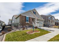 Inviting home with two-car garage, manicured lawn, stone and siding details and concrete stairs to front entry at 8230 S White Crow St, Aurora, CO 80016