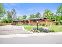 Charming red brick home with landscaped yard, bright orange door and attached garage at 5200 W Rowland Ave, Littleton, CO 80128
