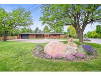 Charming brick home featuring a colorful front door, lush landscaping, and a spacious front yard at 5200 W Rowland Ave, Littleton, CO 80128