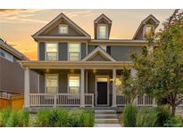 Inviting two-story home featuring a charming front porch, neutral siding, and lush landscaping at 14065 Harrison St, Thornton, CO 80602