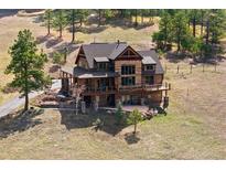 Beautiful log home with a wraparound deck and stone accents surrounded by lush green trees at 280 Hess Ave, Golden, CO 80401