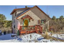 Charming stucco home with unique details, a red deck, and snowy landscape at 347 Buena Vista, Palmer Lake, CO 80133