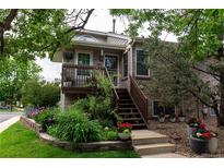 Charming home featuring a cozy front porch, brick accents, and lush landscaping with colorful flowers at 1470 S Quebec Way # 245, Denver, CO 80231