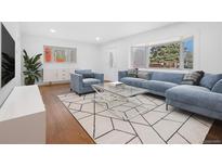 Bright living room with large bay window, comfortable blue seating and a modern geometric-patterned rug at 5730 E 19Th Ave, Denver, CO 80220