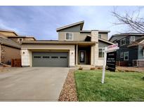 Inviting two-story home featuring a well-kept lawn, stone accents, and a convenient two-car garage at 19925 W 93Rd Ave, Arvada, CO 80007