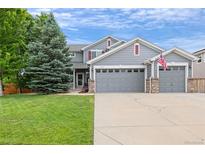 Charming two-story home with a three-car garage, lush green lawn, and mature landscaping at 11870 Cattle Ln, Parker, CO 80134