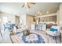Open-concept living room featuring hardwood floors, stylish decor, and seamless flow into kitchen and dining area at 12574 Lake View St, Longmont, CO 80504