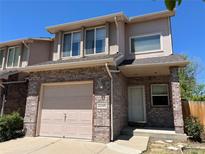 Charming two-story townhome with brick facade, attached garage, and well-maintained landscaping under a clear blue sky at 2035 Overland Dr, Brighton, CO 80601