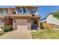 Charming two-story townhome with brick facade, attached garage, and inviting front yard at 2035 Overland Dr, Brighton, CO 80601