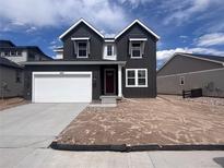 New two-story home featuring a two-car garage, red front door, dark siding, and unfinished front yard at 4284 Ridgewalk Pt, Castle Rock, CO 80108