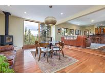 Open dining room with wood-burning stove, view of trees, and hardwood flooring at 167 Independence Cir, Breckenridge, CO 80424