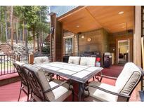 Outdoor patio with dining table, grill, and views of the surrounding forest at 167 Independence Cir, Breckenridge, CO 80424
