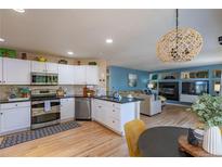 Bright kitchen with white cabinets, stainless steel appliances, hardwood floors, and an open layout to the living area at 8888 S Dudley St, Littleton, CO 80128