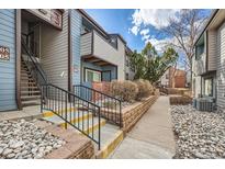 View of the building's exterior, showing the entrance, stairs, and landscaping at 11913 E Harvard Ave # 106, Aurora, CO 80014