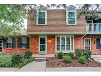 Charming brick home featuring a bay window, lush landscaping, and a cozy entryway at 9060 E Cherry Creek South Dr # E, Denver, CO 80231