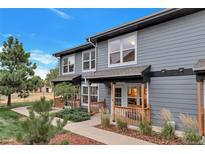 Charming gray two-story home with inviting porch, featuring wood railing and well-maintained landscaping, under a clear blue sky at 1457 S Pierce St, Lakewood, CO 80232