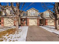 Tan two-story townhome with attached garage and snowy front yard at 15907 E 13Th Ave, Aurora, CO 80011