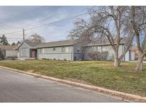 Charming single-story home featuring a freshly painted gray brick exterior and well-maintained front lawn at 7155 E Exposition Ave, Denver, CO 80224