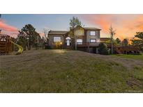 Beautiful two-story home with a lush lawn, trees, large deck, and playground at dusk at 7388 S Ireland Cir, Centennial, CO 80016
