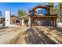 Striking exterior with wood accents, modern garage door, and manicured landscaping at 209 American Way, Breckenridge, CO 80424